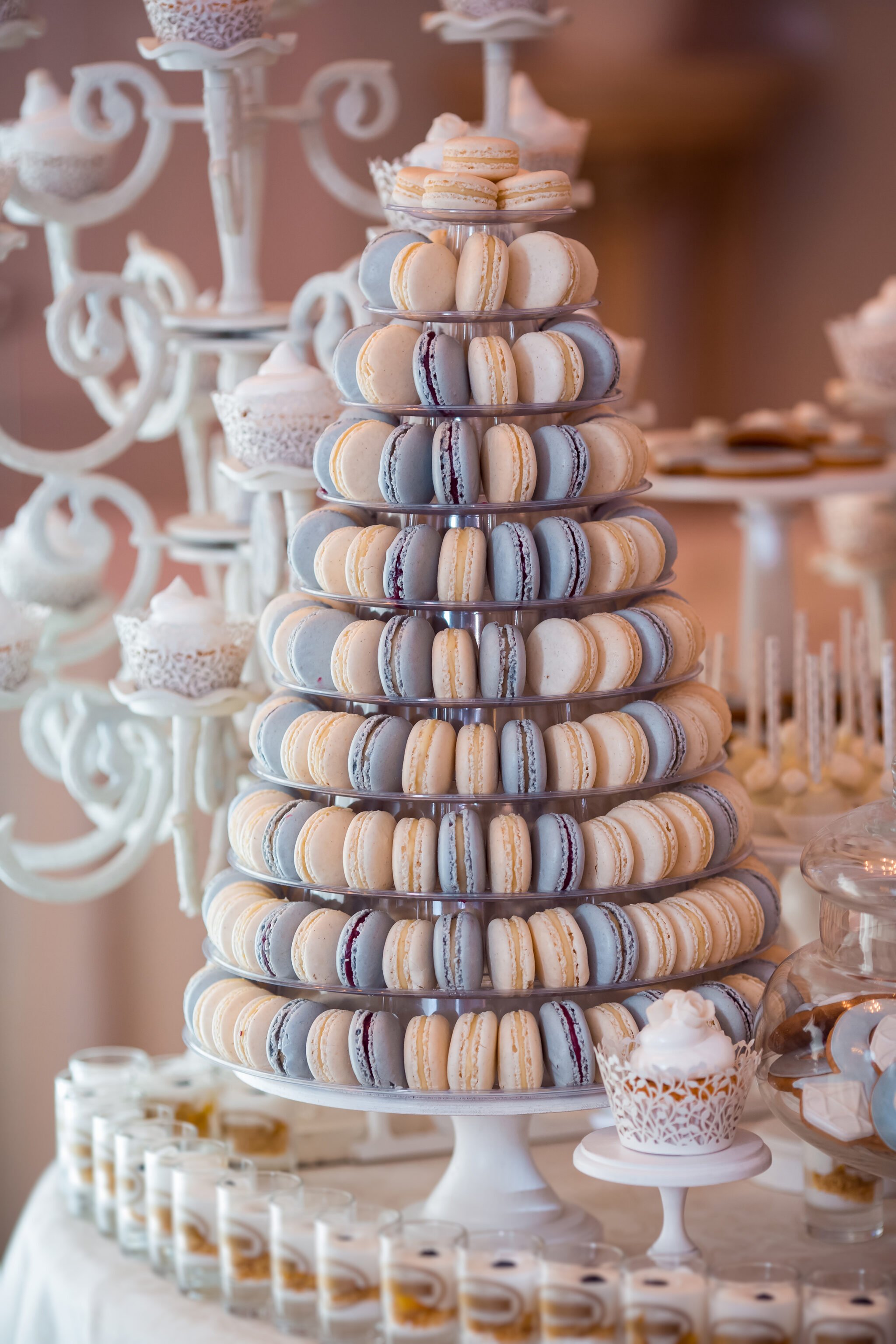 A towering stand of colorful macarons. Macarons are stacked on a white pedestal.