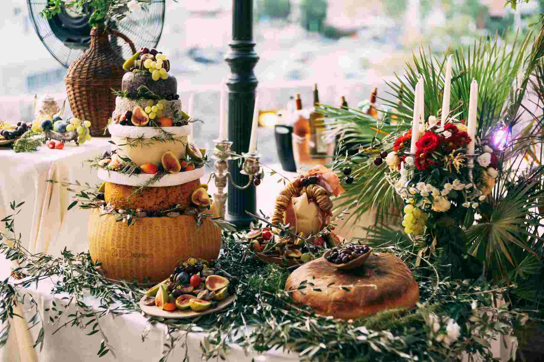 A wedding dessert table with a multi-tiered cake and floral arrangements. The table is decorated with greenery and candles.