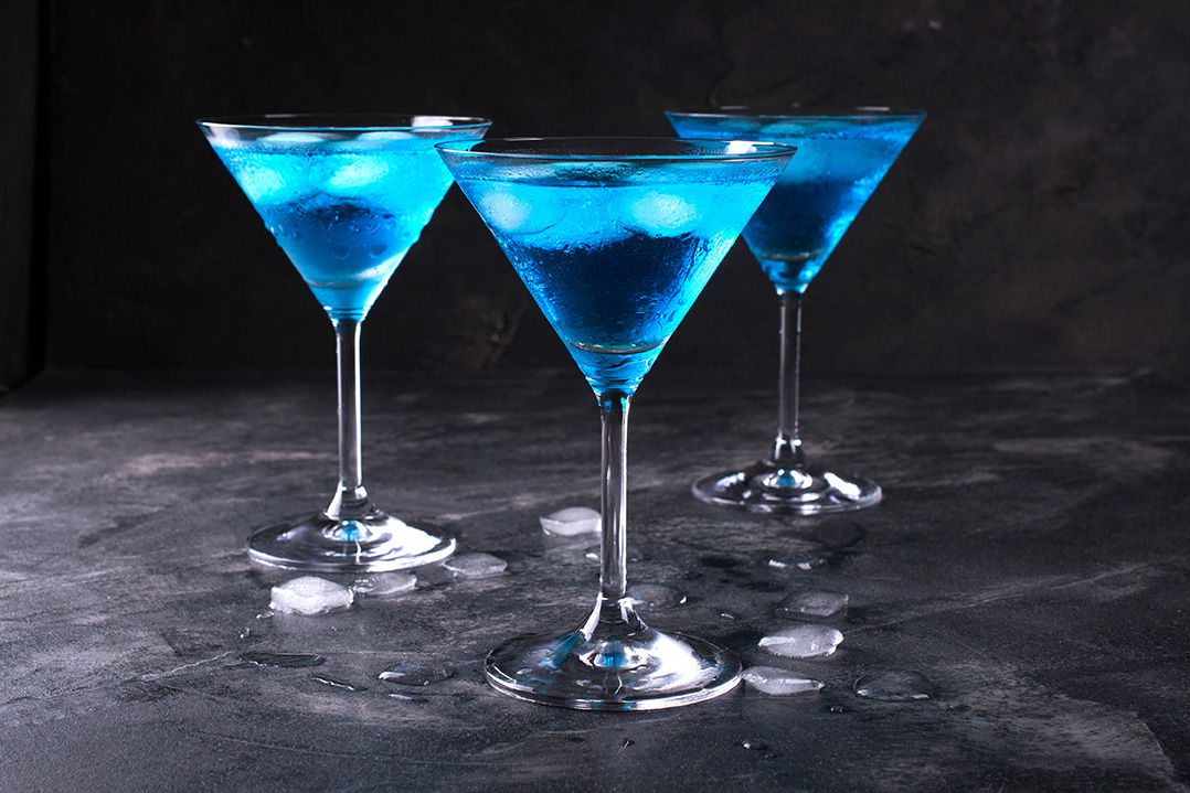 Blue cocktails in martini glasses. Glasses on a dark surface.