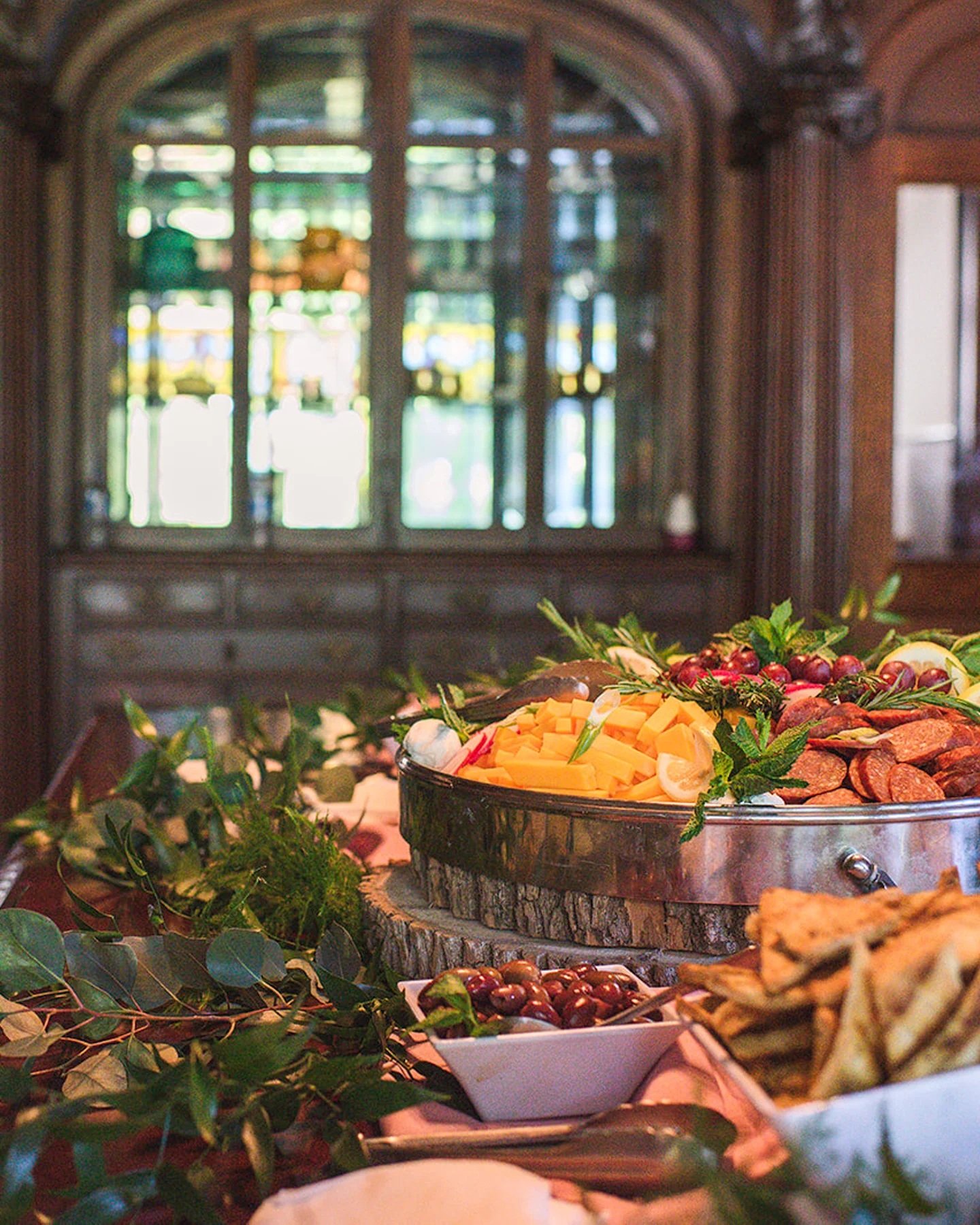 A table with various foods and green leaves. A large bowl of food in the center.