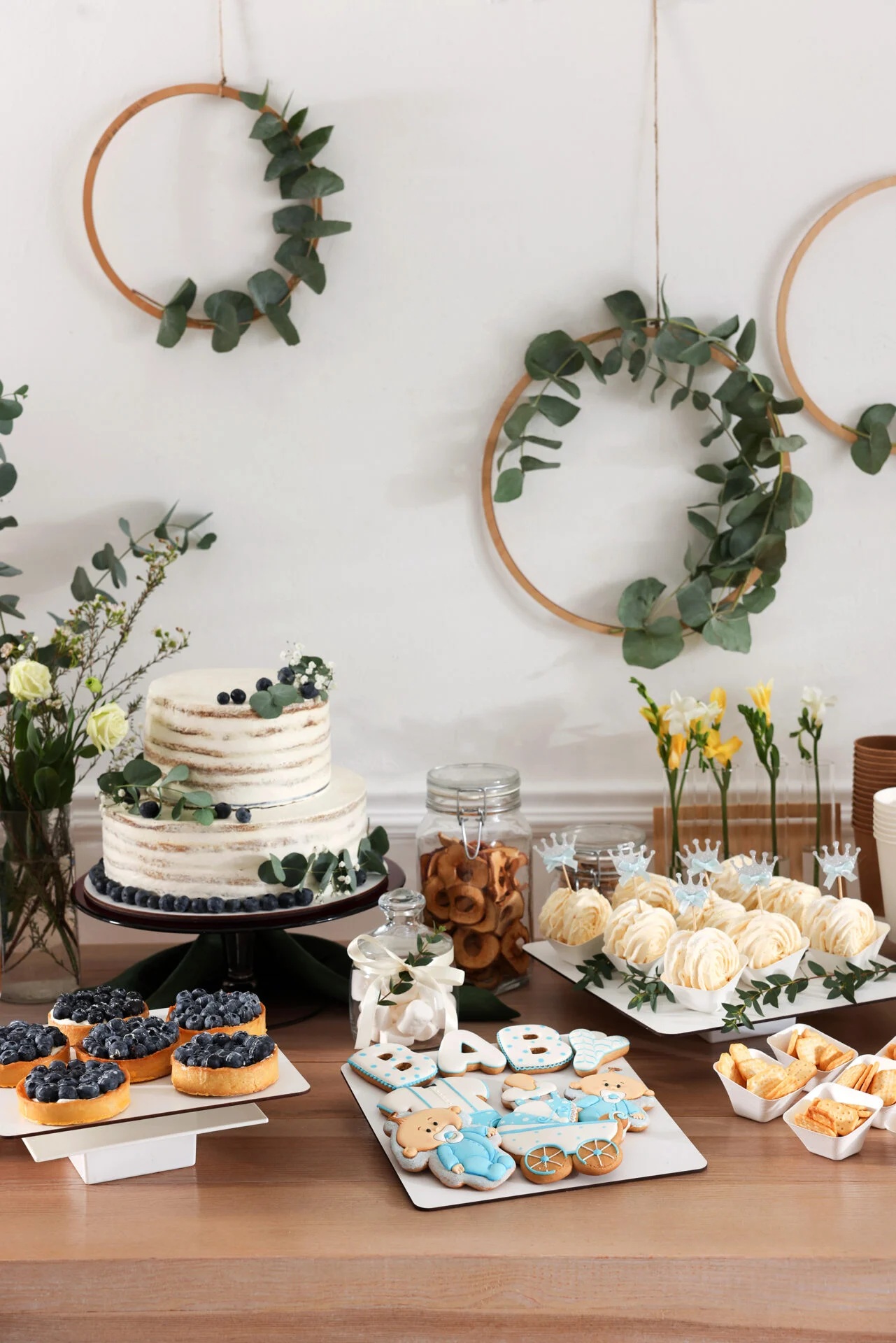 A variety of sweet treats on a table. A cake and cupcakes with white frosting.