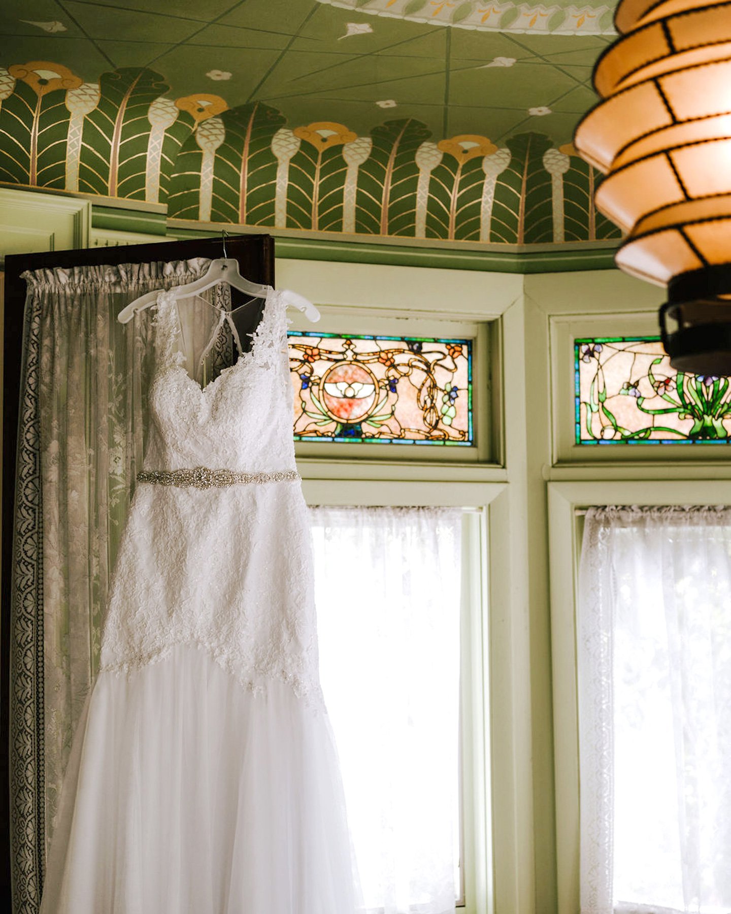 A beautiful white wedding dress. Wedding dress hanging by the window.