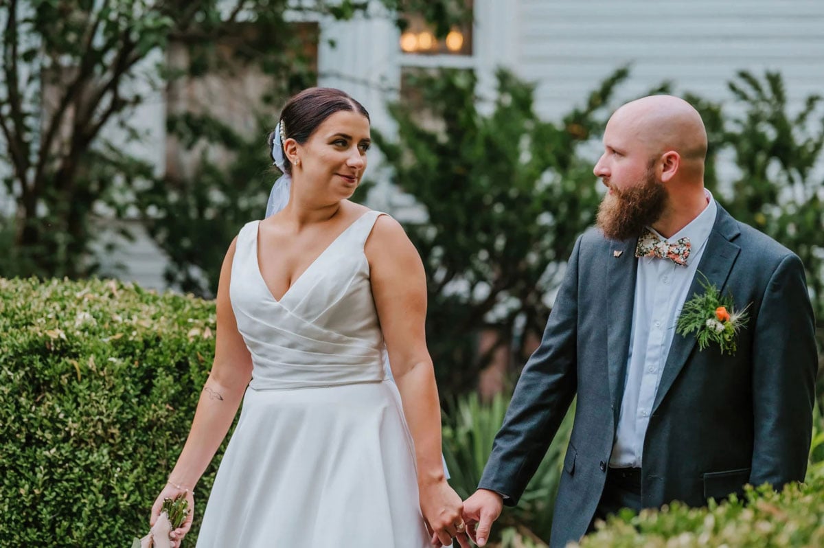 A bride and groom smiling at each other outdoors.