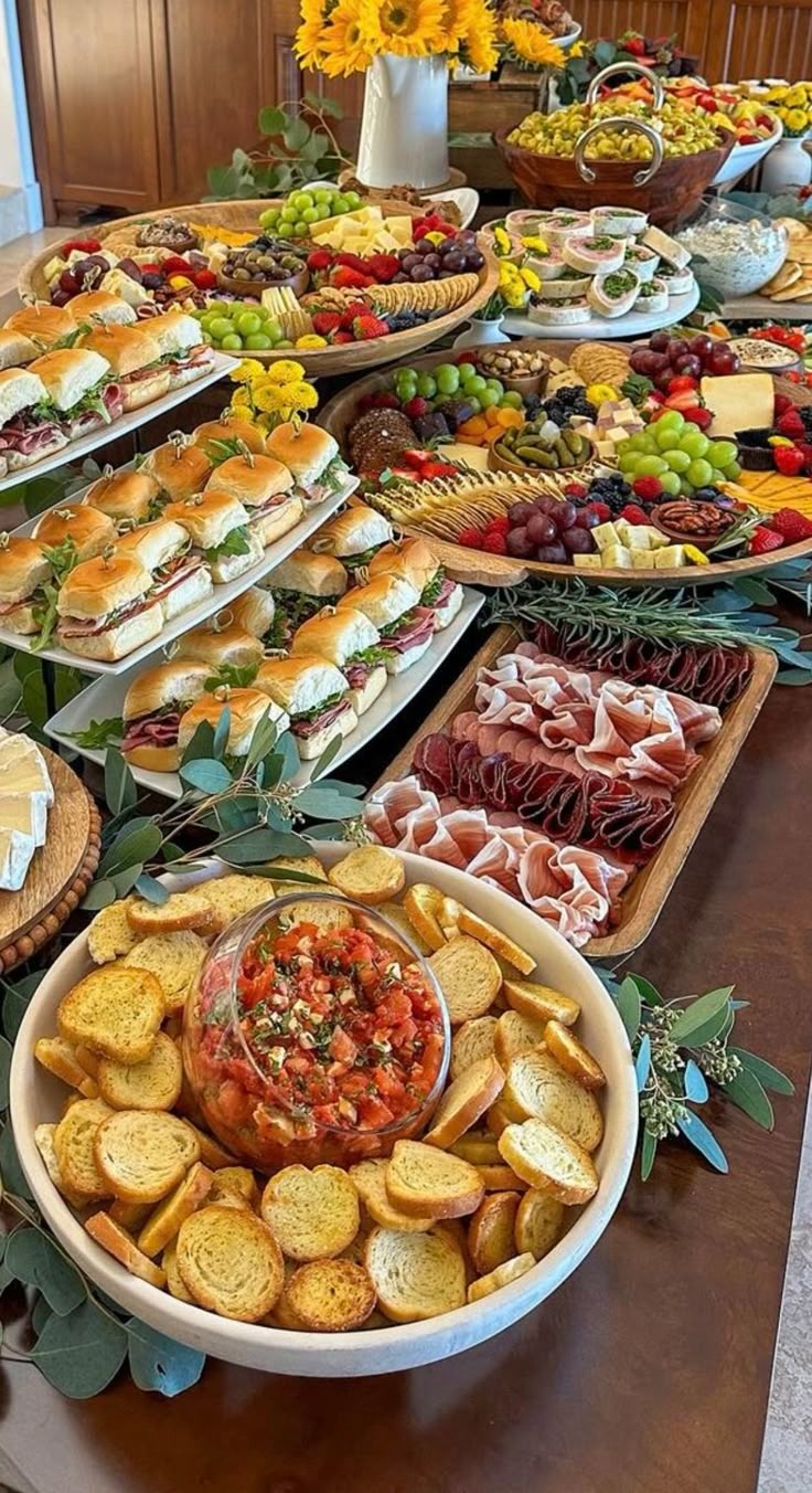 A variety of finger foods and appetizers, including sandwiches, meats, cheeses, and vegetables.