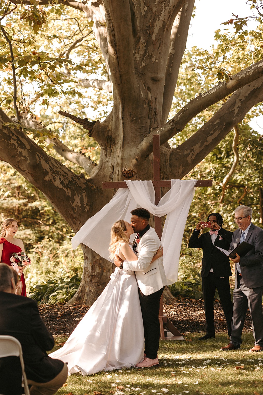 Bride and groom embracing under a tree with white fabric