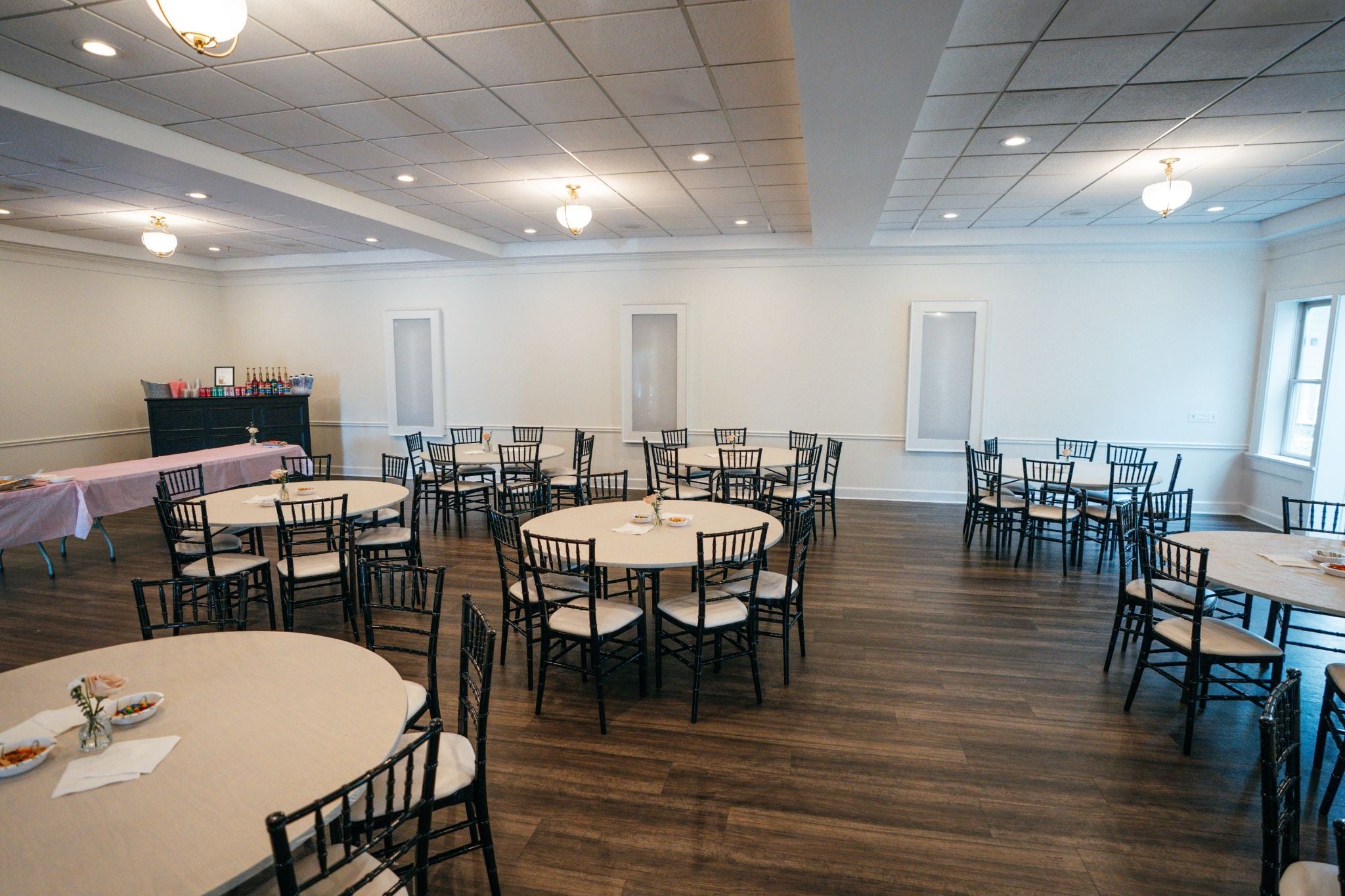 An empty event space with round tables and black chairs