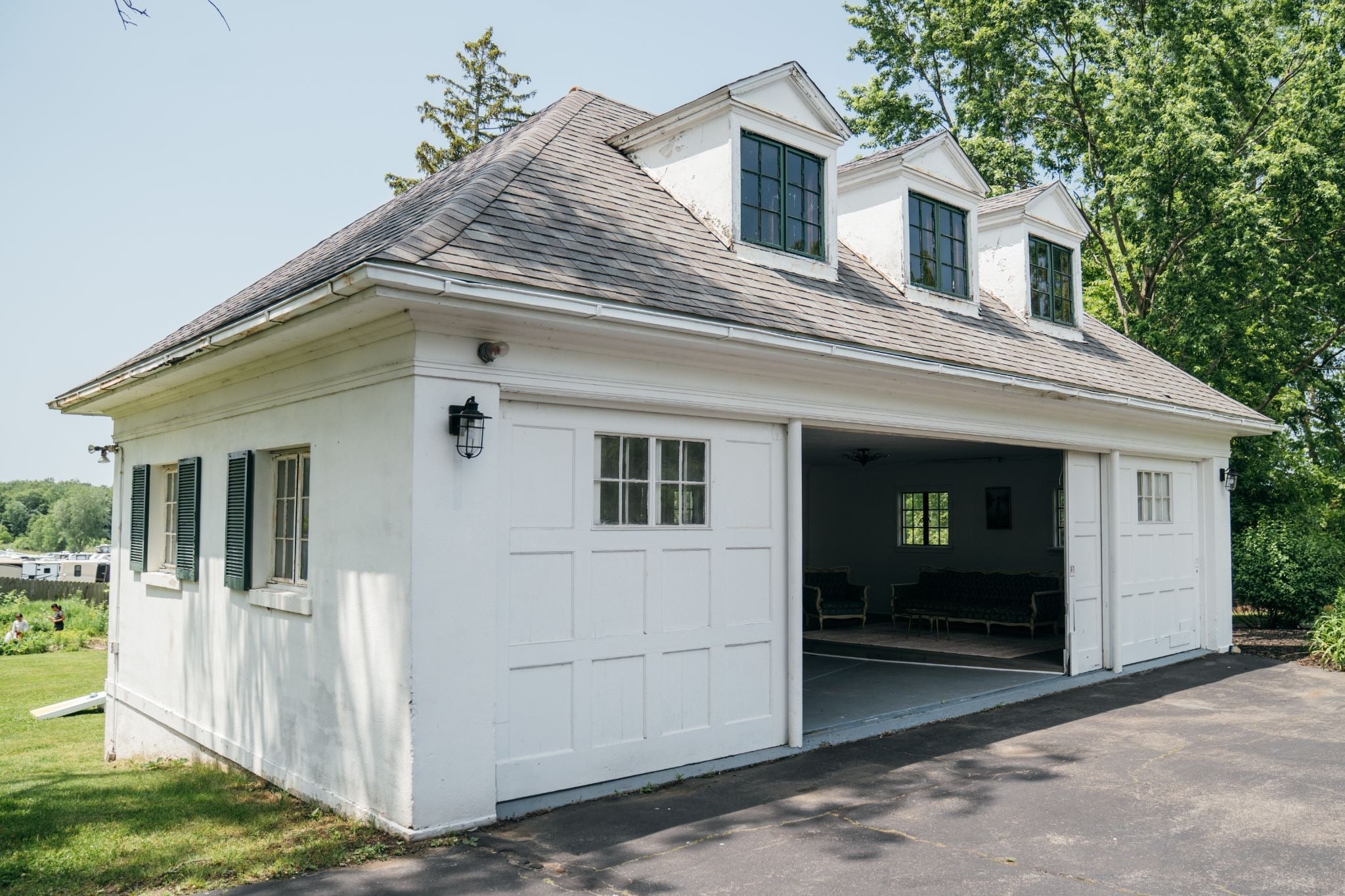 A white garage with an open door and a gray roof. The garage is attached to a driveway.
