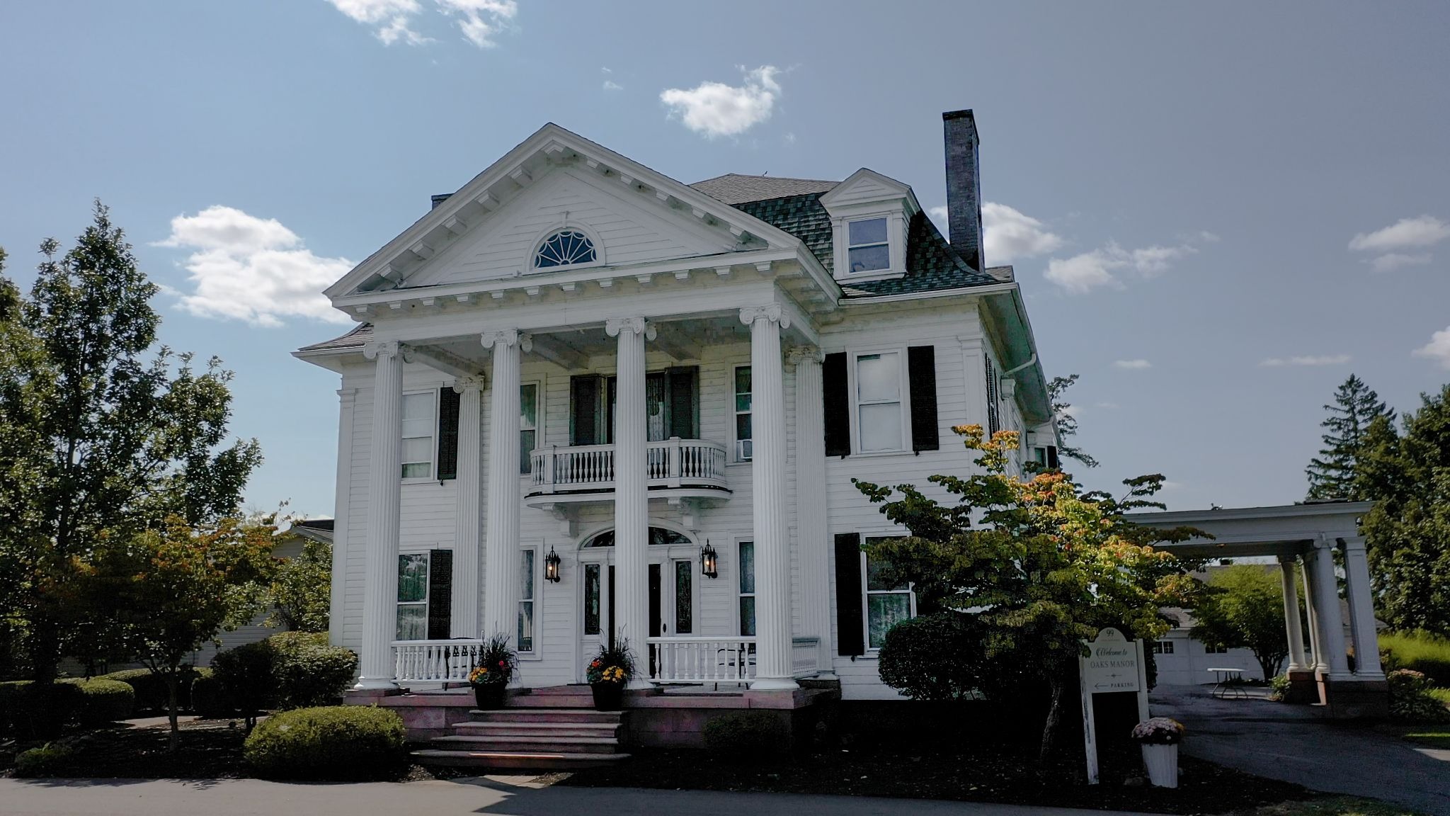 A large white house with columns and a balcony. The house has a classic and elegant design.