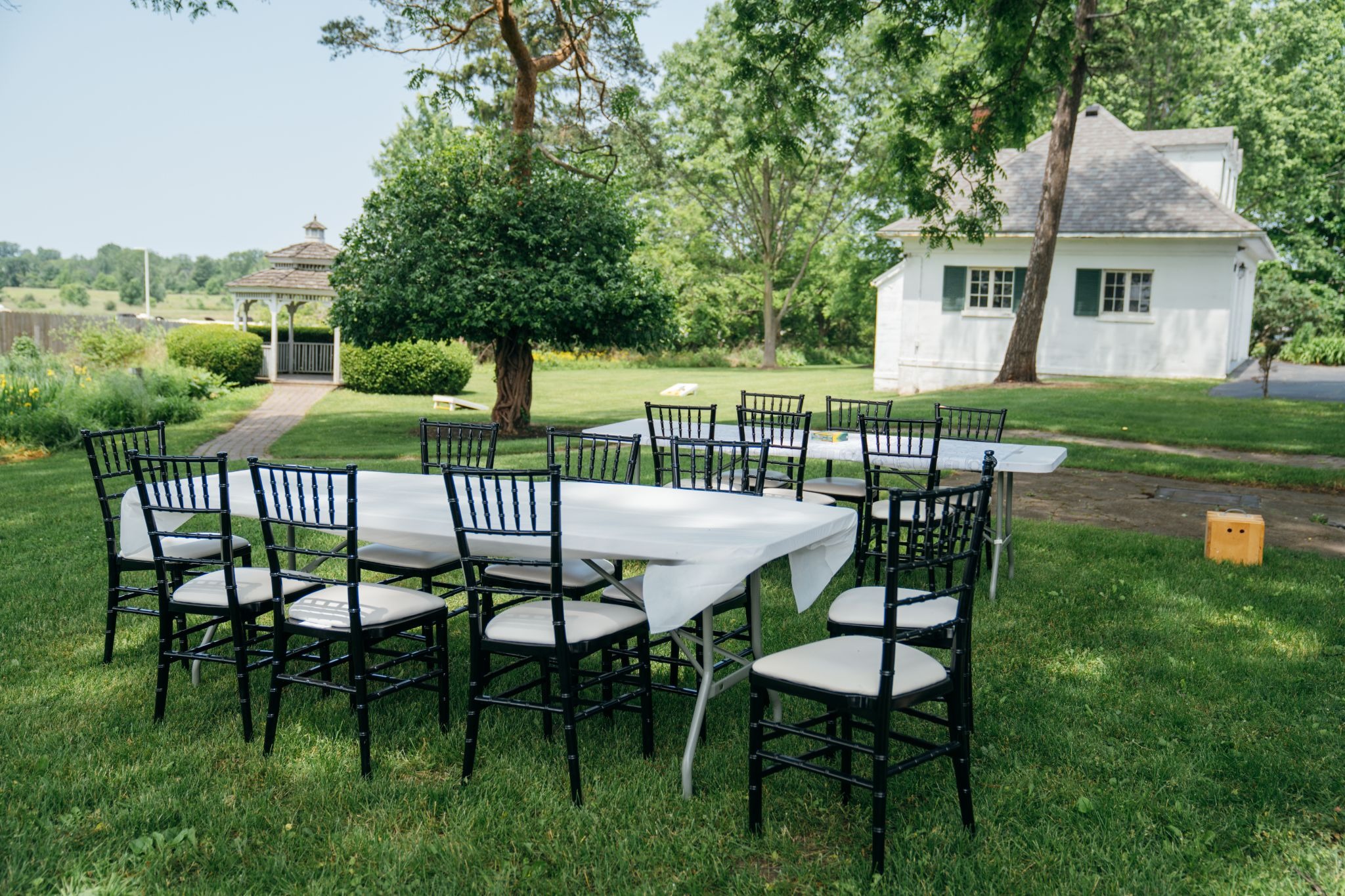 A white table with black chairs on green grass. Perfect outdoor seating arrangement.