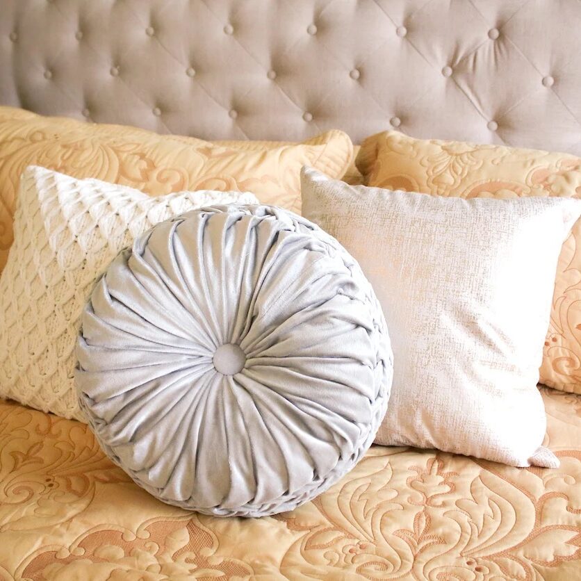 Comfortable bed with tufted headboard and decorative pillows. Soft, luxurious bedding.